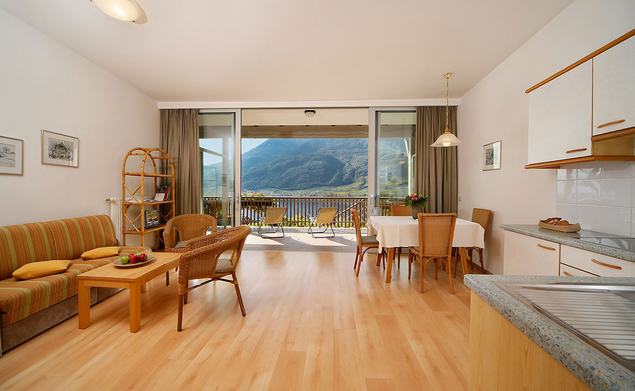 Waohnbereich einer Ferienwohnung im Residence Kalterer See mit Holzboden und Terrassse mit Aussicht auf dem See