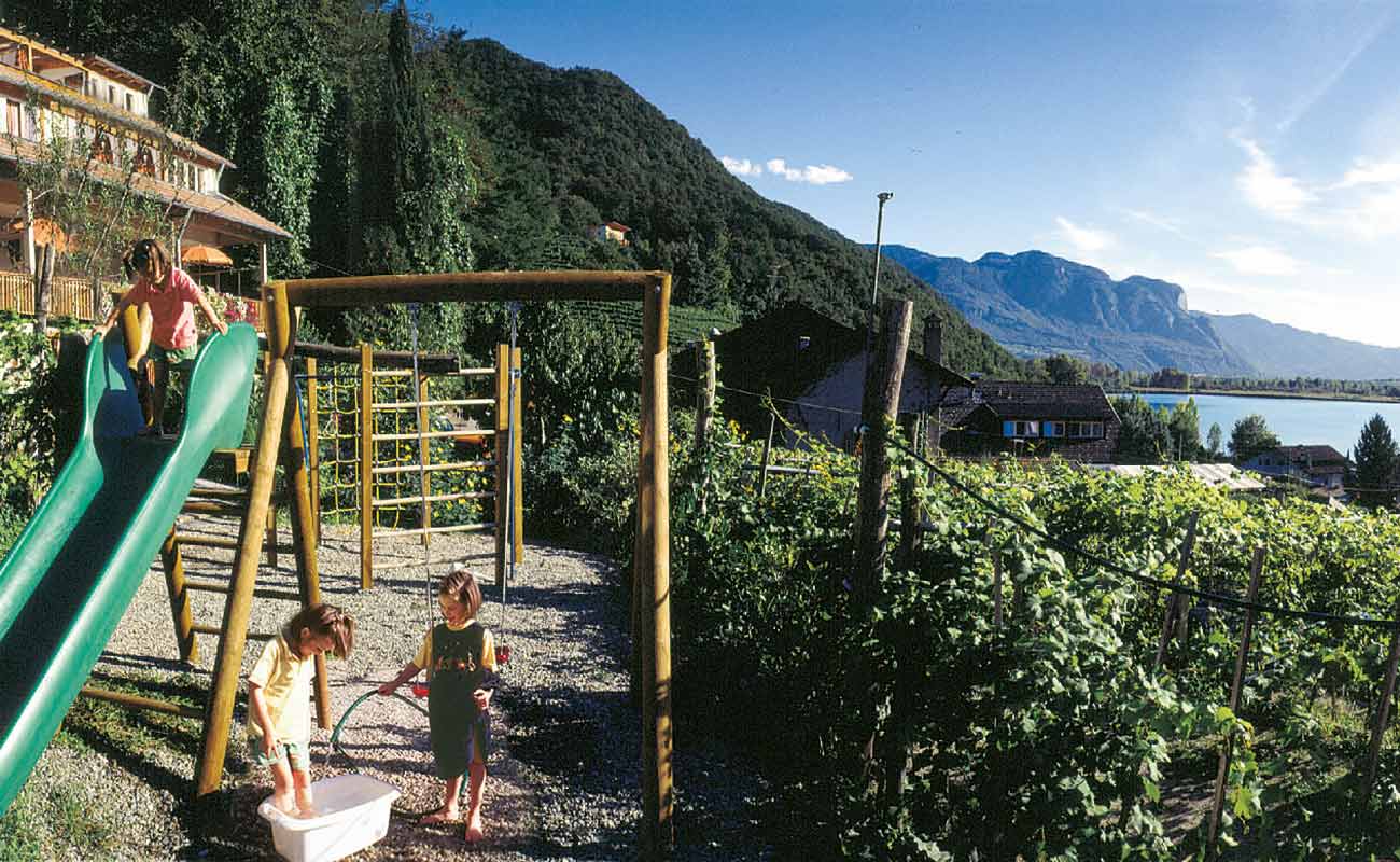 Der Kinderspielplatz mit Rutsche und Schaukel vom Residence Haus Kaltere See umgeben von Reben