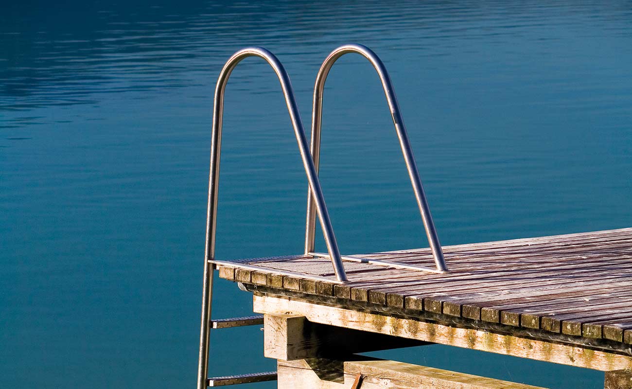 Eine Leiter aus Metall am äußersten Ende eines Badesteges im Kalterersee